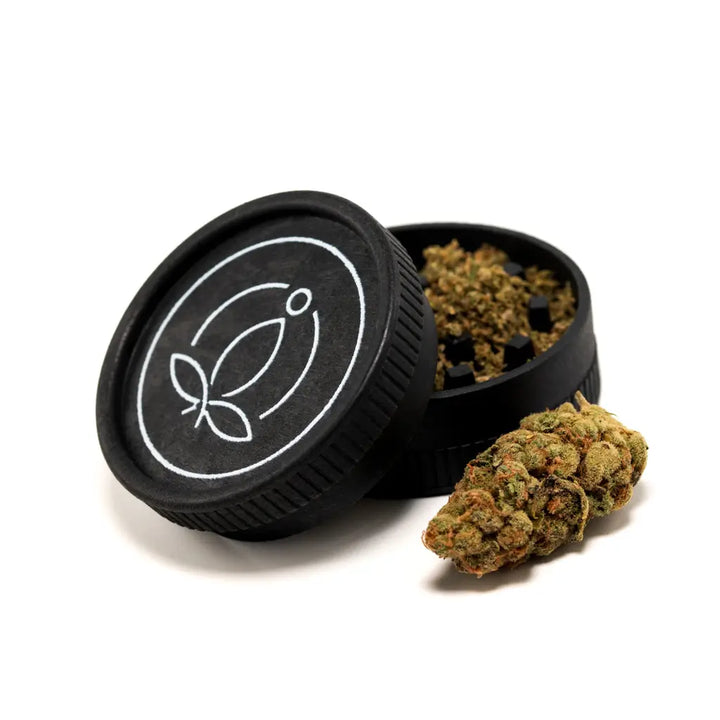 Ein Grinder aus Hanf neben Blüten